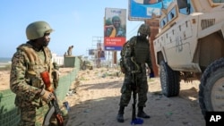 FILE - Ugandan peacekeepers with the African Transition Mission in Somalia (ATMIS) stand next to their armored vehicle on a street in Mogadishu, May 10, 2022.