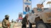 FILE - Ugandan peacekeepers with the African Transition Mission in Somalia (ATMIS) stand next to their armored vehicle on a street in Mogadishu, May 10, 2022.