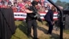 FILE - U.S. Secret Service agents surround the stage as other agents cover Republican presidential candidate former President Donald Trump at a campaign rally, July 13, 2024, in Butler, Pa. 