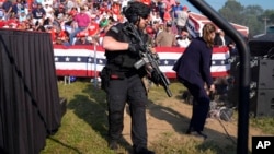 FILE - U.S. Secret Service agents surround the stage as other agents cover Republican presidential candidate former President Donald Trump at a campaign rally, July 13, 2024, in Butler, Pa. 