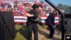 FILE - U.S. Secret Service agents surround the stage as other agents cover Republican presidential candidate former President Donald Trump at a campaign rally in Butler, Pennsylvania, July 13, 2024.