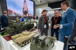Visitors view mockups of ground vehicles as they tour the Russian pavilion during the International Defense Exhibition (IDEX) at the Abu Dhabi International Exhibition Centre, Feb. 20, 2023.