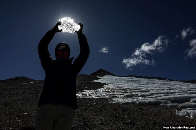 Mountain guide Daniela Pagli holds melted ice from the Iver glacier in the Andes mountain range, Chile, April 4, 2024. REUTERS/Ivan Alvarado