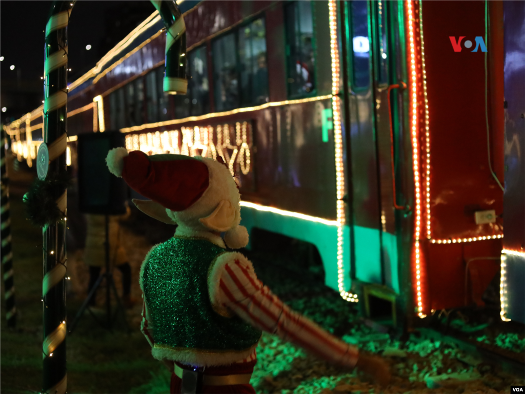 Una persona luce su disfraz de duende frente al tren de Navidad en Bogotá, Colombia.