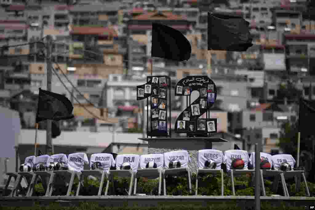 Foto-foto 12 anak-anak dan remaja yang tewas dalam serangan roket di lapangan sepak bola, dan kursi-kursi bertuliskan nama mereka terlihat dipajang di bundaran di desa Majdal Shams, di Dataran Tinggi Golan yang dianeksasi Israel. (AP)&nbsp;