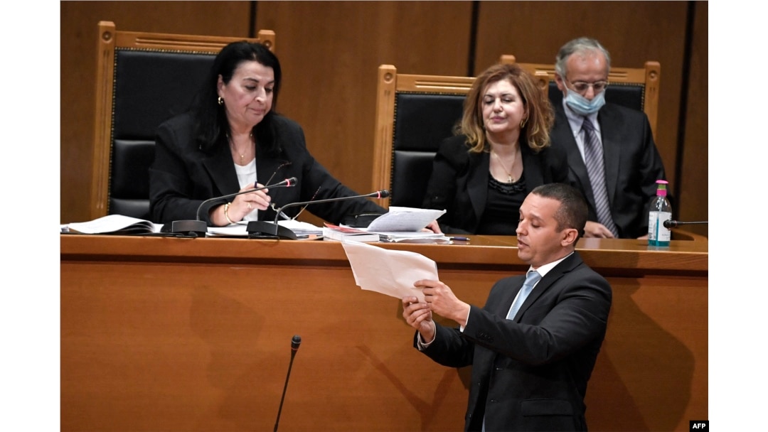 FILE - Ilias Kasidiaris, former Golden Dawn MP and spokesman, who was handed a sentence of 13 years imprisonment, presents documents to presiding judge Maria Lepenioti at the appeals court in Athens, Oct. 21, 2020.
