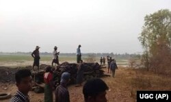 FILE - Men stand over a funeral pyre in Tar Taing village, as they prepare to cremate bodies of those found dead in the nearby village of Nyaung Yin, Myinmu township and in Tar Taing village, Sagaing township, central Myanmar, on March 2, 2023. Soldiers in Myanmar rampaged through several villages, raping, beheading and killing at least 17 people, residents said.