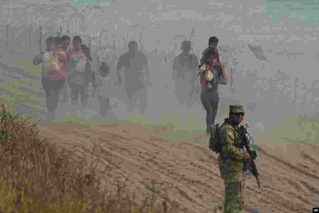 Стражар од Тексас гледа како мигрантите кои го преминале Рио Гранде од Мексико до САД шетаат по жицата, 31 јули 2023 година, во Игл Пас, Тексас.