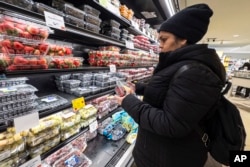 Žena u supermarketu u Njujorku provjerava cijene voća, januar 2024. (Foto: AP/Peter K. Afriyie)