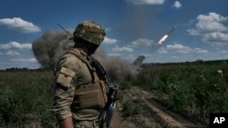 FILE - A Ukrainian soldier watches a Grad multiple launch rocket system firing shells near Bakhmut, Donetsk region, Ukraine, Aug. 13, 2023.