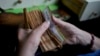 FILE - A worker counts money at a grocery store in Buenos Aires, Argentina, Nov. 21, 2023.