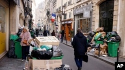 A man walks past uncollected garbage in Paris, March 15, 2023 as sanitation workers are on strike. 