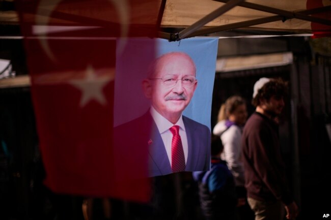 People walk past banners with the photograph of Turkish CHP party leader and Nation Alliance's presidential candidate Kemal Kilicdaroglu in Istanbul, Turkey, Tuesday, April 18, 2023. Turkey is heading toward presidential and parliamentary elections on Sunday May 14, 2023. (AP Photo/Francisco Seco)