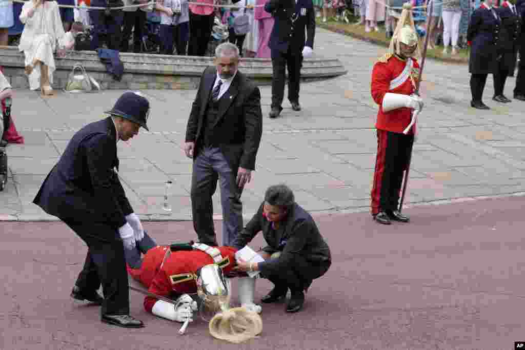 A soldier who fainted gets immediate help ahead of the Order of the Garter service at Windsor Castle, in Windsor, England.