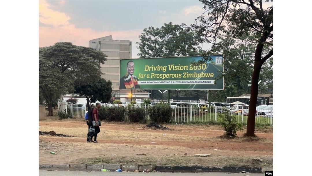 Citizens walk past a banner of President Emmerson Mnangagwa saying Zimbabwe is shaping to be prosperous by 2030 in Harare. (Columbus Mavhunga/VOA)