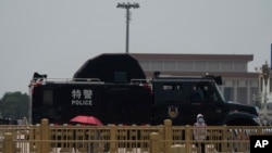 A woman stands near a police vehicle on Tiananmen Square in Beijing, China, June 4, 2024. 