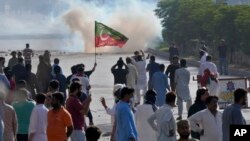FILE - Supporters of Pakistan's former Prime Minister Imran Khan block a road as police fire tear gas to disperse them during a protest in support of Khan in Karachi, Pakistan, May 9, 2023. 