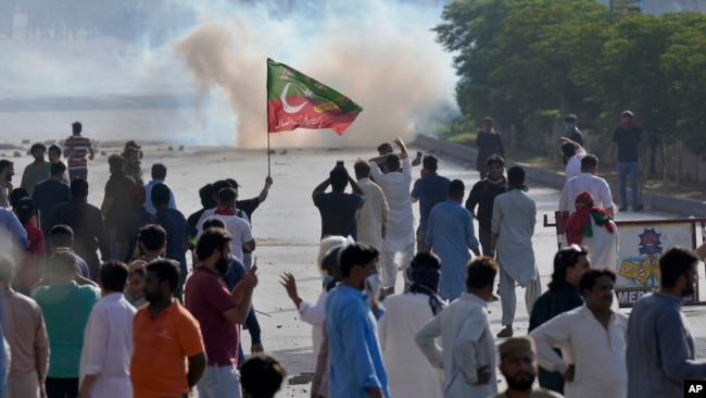 FILE - Supporters of Pakistan's former Prime Minister Imran Khan block a road as police fire tear gas to disperse them during a protest in support of Khan in Karachi, Pakistan, May 9, 2023.