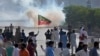 FILE - Supporters of Pakistan's former prime minister Imran Khan block a road as police fire tear gas to disperse them during a protest in support of Khan in Karachi, Pakistan, May 9, 2023. 