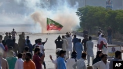 FILE - Supporters of Pakistan's former prime minister Imran Khan block a road as police fire tear gas to disperse them during a protest in support of Khan in Karachi, Pakistan, May 9, 2023. 