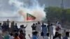 Para pendukung dari mantan Perdana Menteri Pakistan Imran Khan memblokade jalan di saat polisi menembakkan gas air mata untuk membubarkan massa dalam demo di Karachi, Pakistan, pada 9 Mei 2023. (Foto: AP/Fareed Khan)