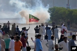 Supporters of Pakistan's former Prime Minister Imran Khan block a road as police fire tear gas to disperse them during a protest in support of Khan in Karachi, Pakistan, May 9, 2023.