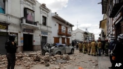 Rescue workers stand next to a car crushed by debris after an earthquake in Cuenca, Ecuador, March 18, 2023. The U.S. Geological Survey reported an earthquake with a magnitude of 6.7 about 50 miles south of Guayaquil. 