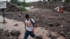 ARCHIVO - Un hombre cruza un arroyo en una carretera después de que un río se desbordó en Verapaz, El Salvador, el domingo 30 de mayo de 2010.