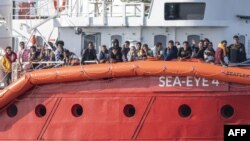 Para migran yang diselamatkan di Laut Mediterania bersiap turun dari kapal Sea-Eye 4 pada 7 November 2021 di Pelabuhan Trapani, Sisilia, Italia. (Foto: AFP)