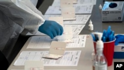 FILE - A nurse processes COVID-19 rapid antigen tests at a testing site in Long Beach, Calif., Jan. 6, 2022.