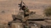 An Israeli soldiers walks on the top of a stationed tank near the border with Lebanon, in Israel, Oct. 14, 2023. 