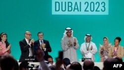 Le président de la COP28, Sultan Ahmed Al Jaber (centre), applaudit parmi d'autres responsables à la COP28 à Dubaï le 13 décembre 2023.