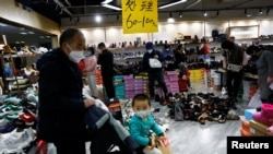 FILE - Customers shop at a shoe store during a clearance sale at a mall in Beijing, China, Jan. 15, 2023.