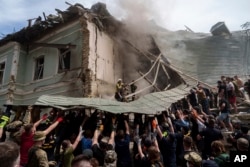 FILE - Emergency services work at the site of Okhmatdyt children's hospital hit by Russian missiles, in Kyiv, July 8, 2024. For Ukrainian competitors in Paris for the Olympics, joy goes hand in hand with sorrow.