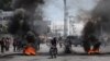 Motoristas pasan junto a una barricada en llamas después de que el gobierno dijera que extendería el estado de emergencia por otro debido a una escalada de violencia de las pandillas que buscan derrocar al Primer Ministro Ariel Henry, en Puerto Príncipe, Haití, el 7 de marzo.