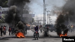 Motoristas pasan junto a una barricada en llamas después de que el gobierno dijera que extendería el estado de emergencia por otro debido a una escalada de violencia de las pandillas que buscan derrocar al Primer Ministro Ariel Henry, en Puerto Príncipe, Haití, el 7 de marzo.