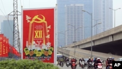 FILE - Traffic ride past a Communist party poster in Hanoi, Vietnam on Jan. 19, 2016. 