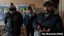 Yuri, right, Andrii, center, and Vadim say that changing the name of their town didn’t bring any help at all, in New York, Ukraine, on Feb. 20, 2023.