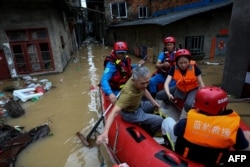 Seorang penduduk desa duduk di perahu karet bersama tim penyelamat di daerah banjir setelah badai di Nanping, provinsi Fujian, China timur, 16 Juni 2024. (CNS / AFP)