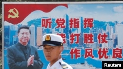 資料照：一名中國解放軍海軍士兵在香港的海軍基地站在有著中國領導人習近平畫像的宣傳標語前。（2016年7月8日）