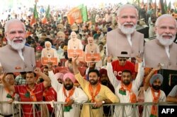 Pendukung Partai Bharatiya Janta (BJP) yang berkuasa memegang gambar Perdana Menteri India yang juga merupakan pemimpin mereka, Narendra Modi, dalam kampanye pemilu di Amritsar pada 30 Mei 2024. (Foto: AFP)