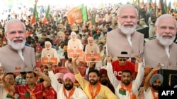 Supporters of the ruling Bharatiya Janta Party (BJP) hold cutouts of India's Prime Minister and their leader, Narendra Modi, as they shout slogans during an election campaign rally in Amritsar on May 30, 2024.