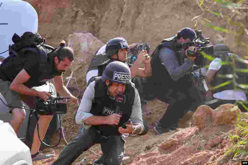 Reporters take cover upon hearing sirens warning of an incoming rocket attack from Gaza, in the southern Israeli city of Sderot amid ongoing battles between Israel and the Palestinian militant group Hamas.