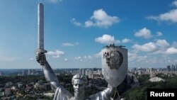 Workers take down a Soviet emblem from the shield of the &#39;Motherland&#39; monument at a compound of the World War II museum in Kyiv, Ukraine.