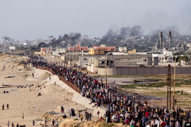 Palestinians wait for aid trucks to cross in central Gaza Strip, May 19, 2024.