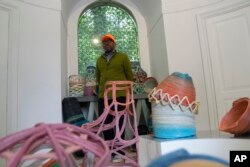 Designer Norman Teague stands next to his creations part of the "Everlasting Plastics" installation at the Biennale International Architecture exhibition, in Venice, Italy, May 17, 2023.