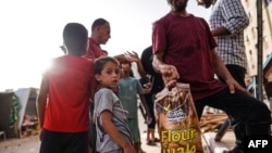 Orang-Orang Palestina mengumpulkan makanan yang dikirim melalui udara di Kota Hamad, di wilayah Khan Yunis di selatan Jalur Gaza, Kamis, 4 Juli 2024. (Foto: Bashar Taleb/AFP)
