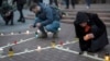 People light candles to honor those killed in the Mariupol drama theatre a year ago, in Kyiv, Ukraine, March 16, 2023. 