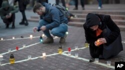 People light candles to honor those killed in the Mariupol drama theatre a year ago, in Kyiv, Ukraine, March 16, 2023. 