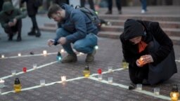People light candles to honor those killed in the Mariupol drama theatre a year ago, in Kyiv, Ukraine, March 16, 2023. 